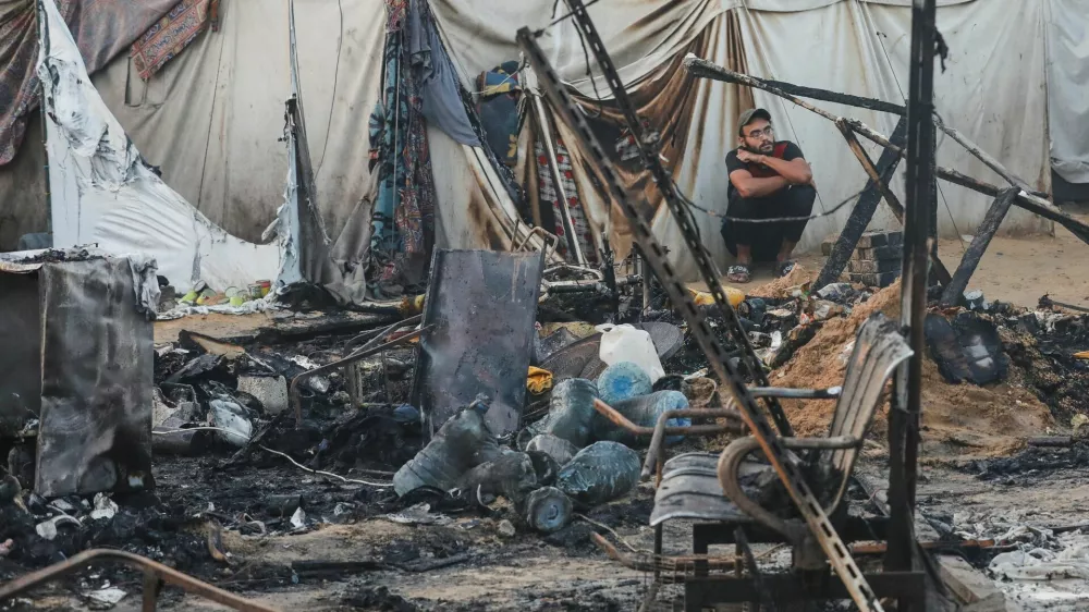 A Palestinian man looks on next to the damage at the site of an Israeli strike on tents sheltering displaced people, amid the Israel-Hamas conflict, at Al-Aqsa Martyrs hospital in Deir Al-Balah in the central Gaza Strip, October 14, 2024. REUTERS/Ramadan Abed   TPX IMAGES OF THE DAY