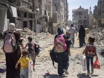 FILE - Palestinian women and their children walk though destruction in the wake of an Israeli air and ground offensive in Jebaliya, northern Gaza Strip after Israeli forces withdrew from the area, on May 31, 2024. (AP Photo/Enas Rami)