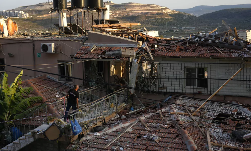 A member of Israeli security forces surveys damage to a home struck by a rocket fired from Lebanon in the town of Majd al-Krum, northern Israel, Wednesday, Oct. 16, 2024. (AP Photo/Ariel Schalit)