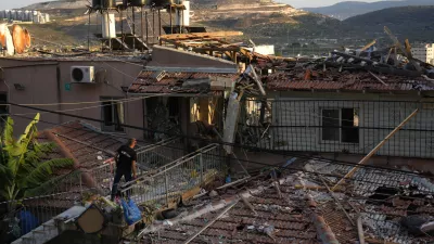 A member of Israeli security forces surveys damage to a home struck by a rocket fired from Lebanon in the town of Majd al-Krum, northern Israel, Wednesday, Oct. 16, 2024. (AP Photo/Ariel Schalit)