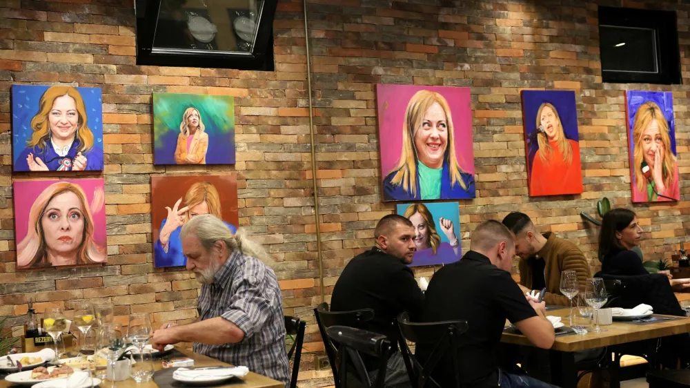 Customers eat a meal as portrait paintings by artist Helidon Haliti of Italy's Prime Minister Giorgia Meloni hang on the walls of "Trattoria Meloni" just outside a migrant processing camp set up by the Italian government, in Shengjin, Albania, October 15, 2024. REUTERS/Florion Goga