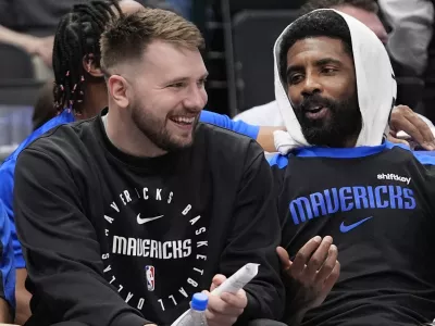 Sitting on the bench Dallas Mavericks guard Luka Doncic, left, shares a laugh with teammate fellow guard Kyrie Irving during a preseason NBA basketball game against the Milwaukee Bucks Thursday, Oct. 17, 2024, in Dallas. (AP Photo/LM Otero)