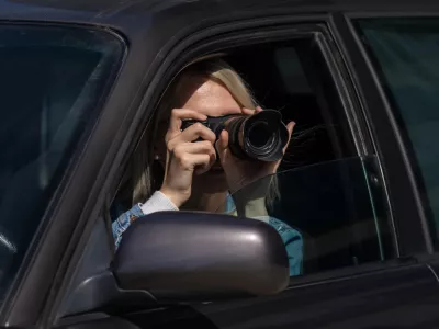 Hidden photographing. Paparazzi Concep Photographer uses his professional camera. Photographer girl in car window. Mobile reporter. Photojournalist at work. Detective or investigator. / Foto: Yaraslau Mikheyeu