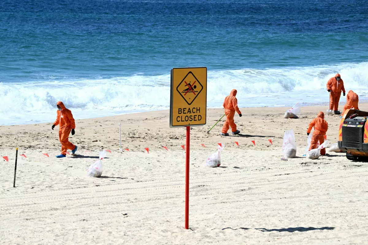 Workers in protective clothing clean up unknown debris washed up on Coogee Beach, Sydney, Australia October 17, 2024. AAP/Dan Himbrechts via REUTERS  ATTENTION EDITORS - THIS IMAGE WAS PROVIDED BY A THIRD PARTY. NO RESALES. NO ARCHIVE. AUSTRALIA OUT. NEW ZEALAND OUT. NO COMMERCIAL OR EDITORIAL SALES IN NEW ZEALAND. NO COMMERCIAL OR EDITORIAL SALES IN AUSTRALIA.