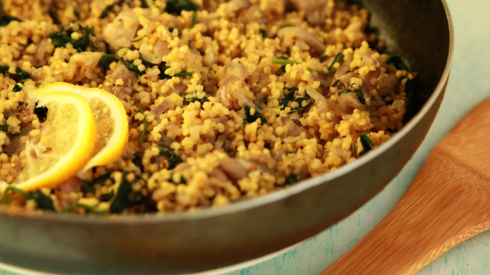 Vegetarian couscous with mushrooms and spinach. Vegan dish with millet in the frying pan. Close up. / Foto: Lora-sutyagina