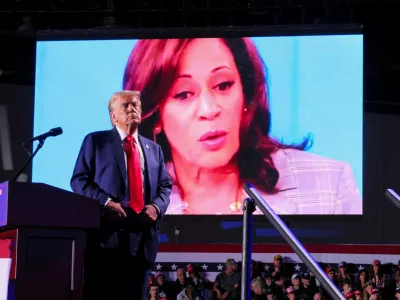 Republican presidential nominee and former U.S. President Donald Trump looks on as Democratic presidential nominee and U.S. Vice President Kamala Harris' face appears as a video plays on a screen, during a rally at Huntington Place in Detroit, Michigan, U.S. October 18, 2024. REUTERS/Brian Snyder