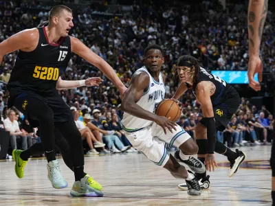 Minnesota Timberwolves guard Anthony Edwards, center, drives to the basket between Denver Nuggets center Nikola Jokic, left, and forward Aaron Gordon in the second half of Game 7 of an NBA second-round playoff series Sunday, May 19, 2024, in Denver. (AP Photo/David Zalubowski)