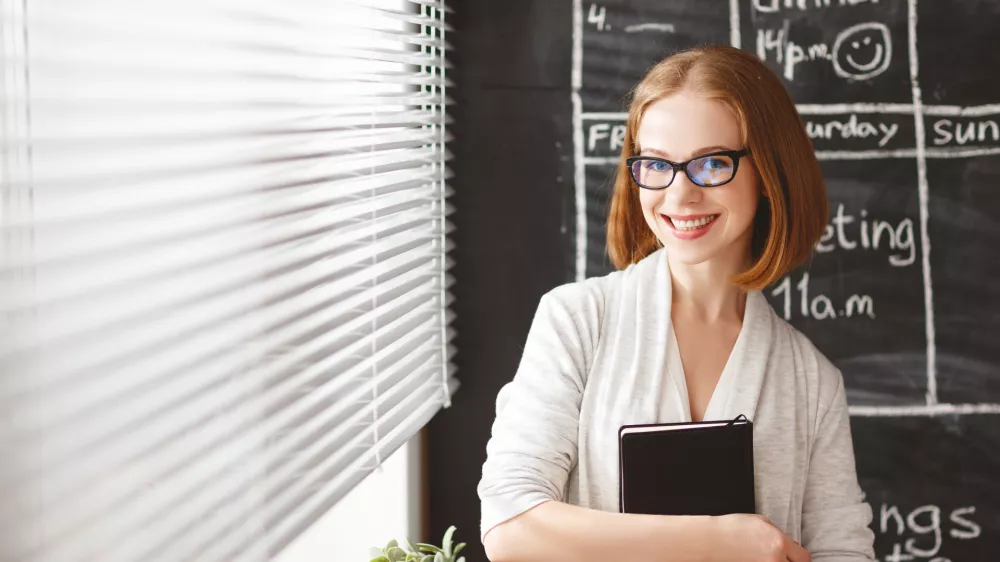 Happy businesswoman woman at school board with schedule planning and notepad