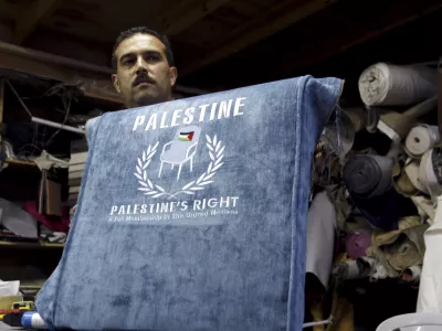 FILE - In this Sunday Aug. 28, 2011 file photo, a Palestinian worker shows a chair covered with embroidered blue upholstery featuring a Palestinian flag and the text: "Palestine, Palestine's Right. A Full Membership in the United Nations", at a workshop in the West Bank city of Jenin. The Palestinians are resigned to defeat in their quest for full membership at the United Nations, officials said Wednesday, Nov. 9, 2011, and have already started work on their backup plan: seeking an upgraded observer status that would give them access to key international organizations. (AP Photo/Mohammed Ballas, File)