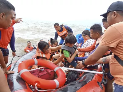 In this photo provided by the Philippine Coast Guard, residents alight a rubber boat after being ferried to safer grounds in Batangas province, Philippines on Friday, Oct. 25, 2024. (Philippine Coast Guard via AP)