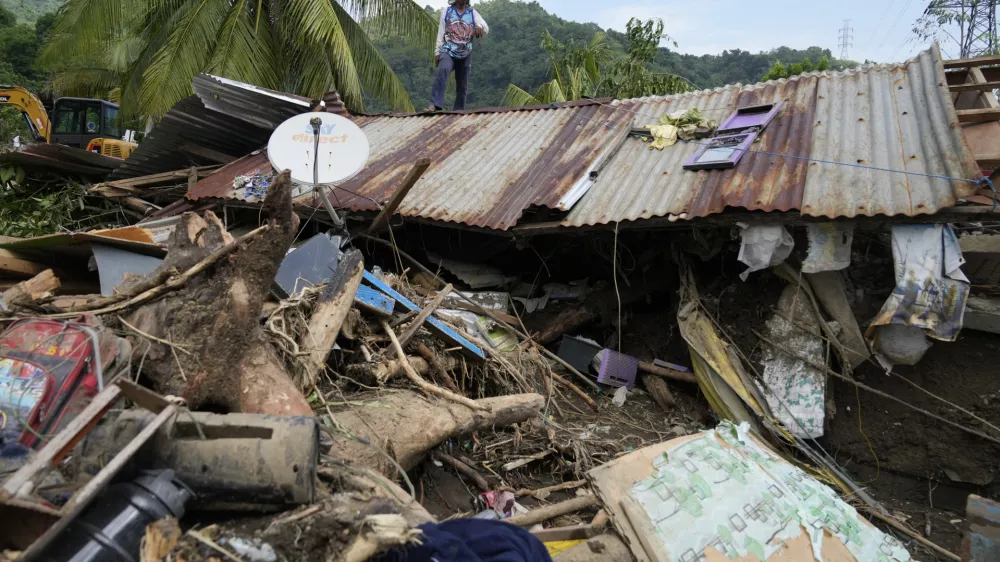 Marcelino Aringo stands on top of a damaged house after a landslide triggered by Tropical Storm Trami recently struck Talisay, Batangas province, Philippines, Saturday, Oct. 26, 2024. (AP Photo/Aaron Favila)