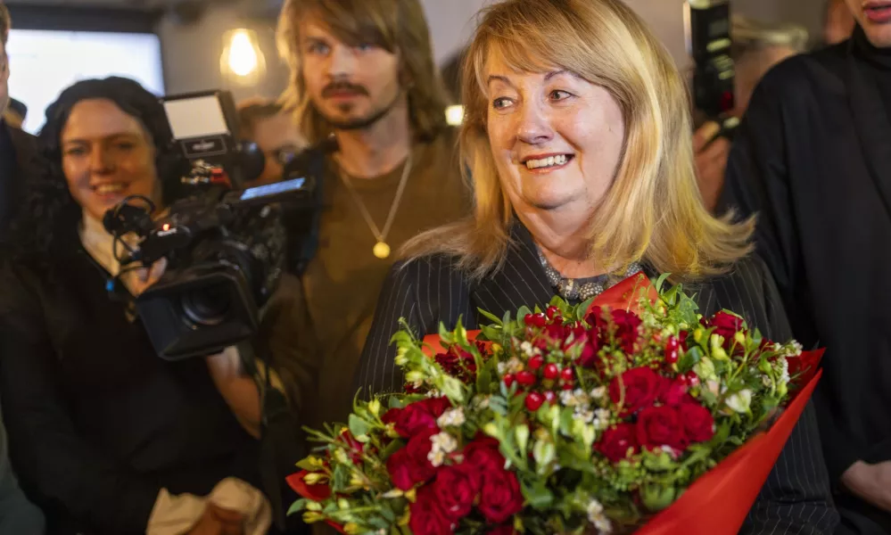 Leader of the Social Democratic Party Vilija Blinkeviciute, center, smiles as she waits for the results of the second round of Lithuania's parliamentary election, in an office in Vilnius, Lithuania, Sunday, Oct. 27, 2024. (AP Photo/Mindaugas Kulbis)