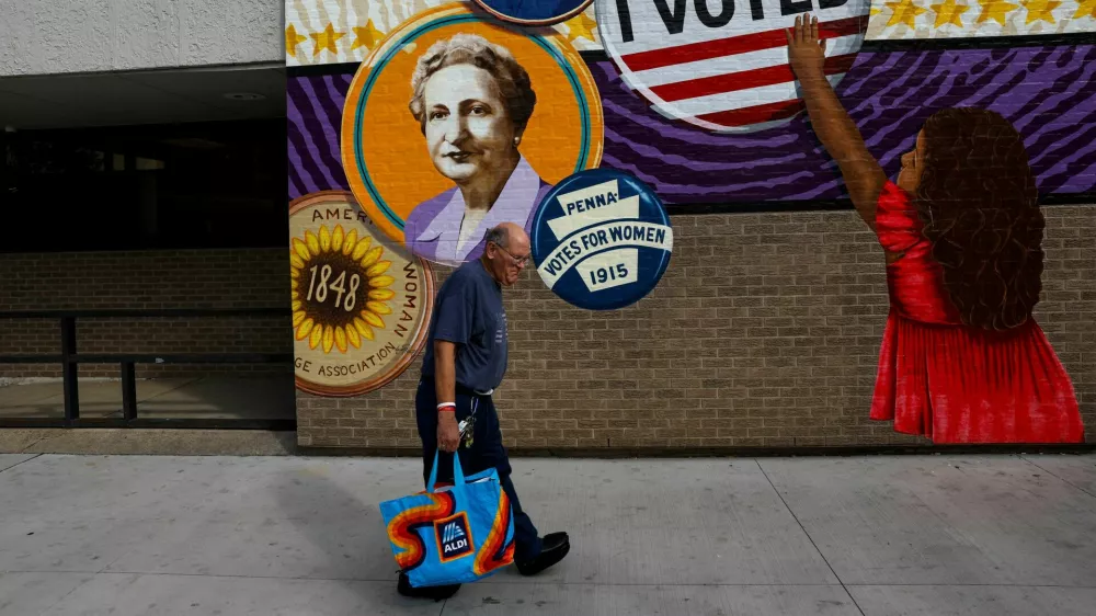 A man walks by a mural in the election battleground city of Erie, Pennsylvania, U.S., October 23, 2024. REUTERS/Shannon Stapleton