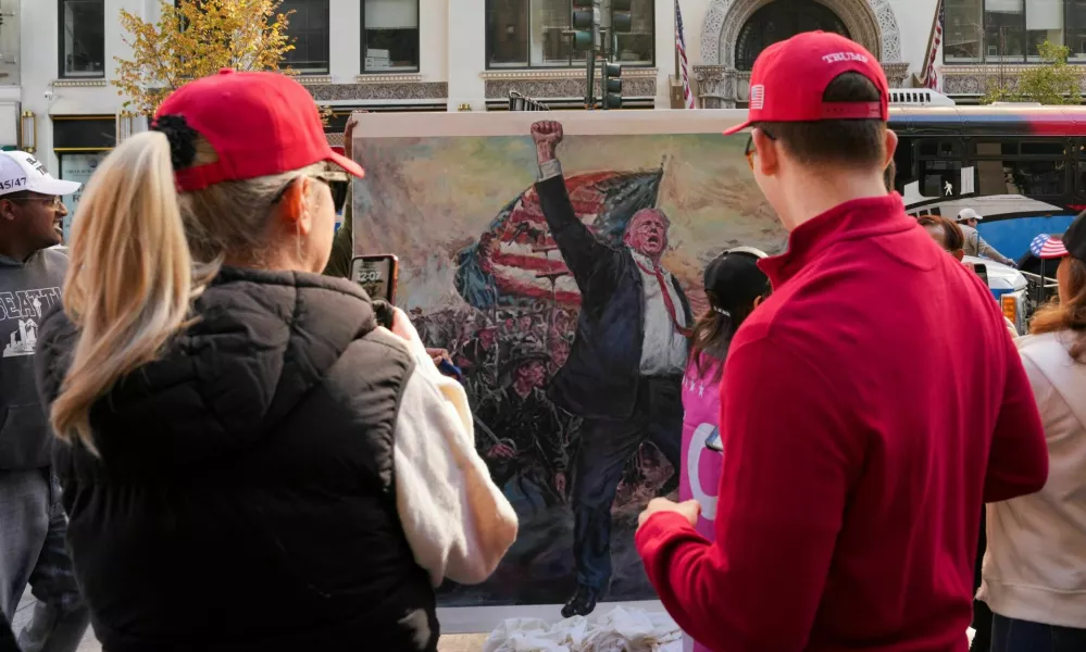 People look at an artwork depicting Republican presidential nominee and former U.S. President Donald Trump on the day of a rally for Trump, in New York, U.S., October 27, 2024. REUTERS/David Dee Delgado