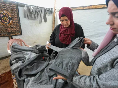 Palestinian Nidaa Attia (R) and another woman display winter clothes they sewed for displaced people from from blankets, amid clothing shortages, at a tent in Khan Younis in the southern Gaza Strip, October 26, 2024. REUTERS/Ramadan Abed