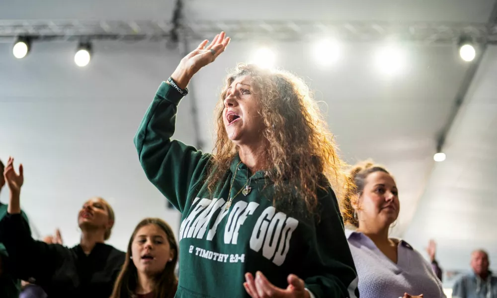 A member of Pastor Greg Locke's Global Vision Bible Church raises her hand during worship service in Mount Juliet, Tennessee, U.S. October 27, 2024. REUTERS/Seth Herald   TPX IMAGES OF THE DAY