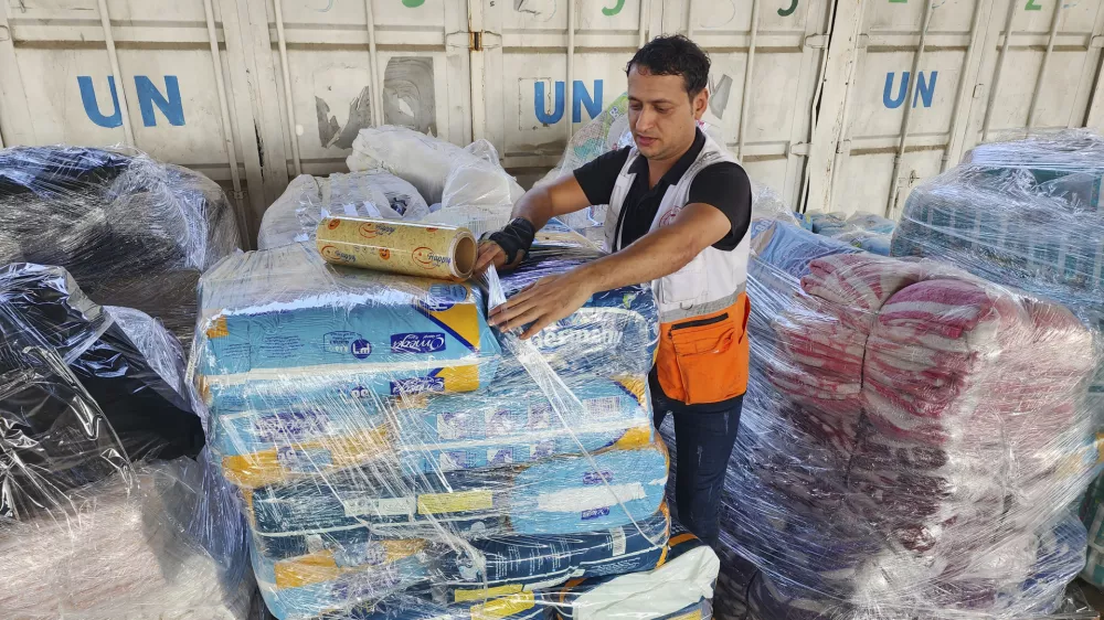 FILE - United Nations and Red Crescent workers prepare the aid for distribution to Palestinians at UNRWA warehouse in Deir Al-Balah, Gaza Strip, on Monday, Oct. 23, 2023. (AP Photo/Hassan Eslaiah, File)