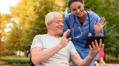 A nurse and an elderly patient who is sitting in a wheelchair, watching something interesting in the old man's tablet / Foto: Vadimguzhva