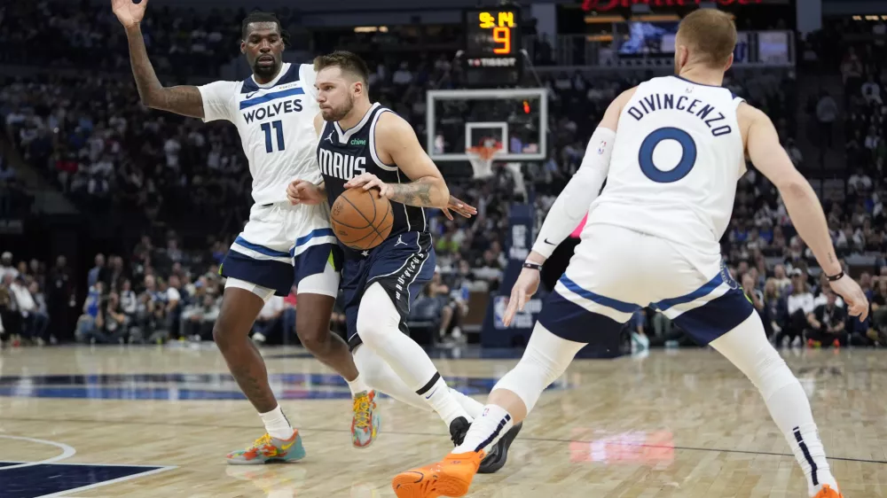 Dallas Mavericks guard Luka Doncic, center, works toward the basket as Minnesota Timberwolves center Naz Reid (11) and guard Donte DiVincenzo (0) defend during the second half of an NBA basketball game, Tuesday, Oct. 29, 2024, in Minneapolis. (AP Photo/Abbie Parr)