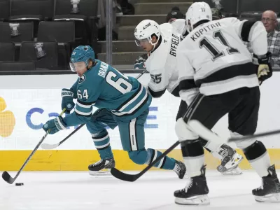 San Jose Sharks center Mikael Granlund (64) reaches for the puck in front of Los Angeles Kings right wing Quinton Byfield, middle, and center Anze Kopitar (11) during the first period of an NHL hockey game in San Jose, Calif., Tuesday, Oct. 29, 2024. (AP Photo/Jeff Chiu)