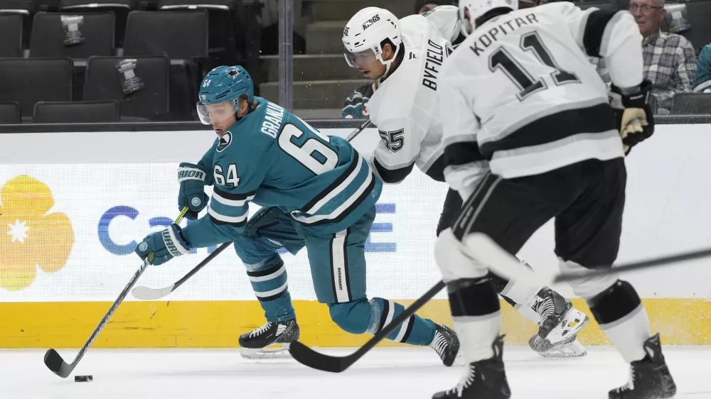 San Jose Sharks center Mikael Granlund (64) reaches for the puck in front of Los Angeles Kings right wing Quinton Byfield, middle, and center Anze Kopitar (11) during the first period of an NHL hockey game in San Jose, Calif., Tuesday, Oct. 29, 2024. (AP Photo/Jeff Chiu)