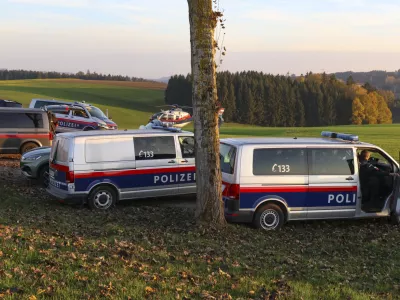 Police vehicles and a police helicopter stand near a field in the village Fraunschalg near Altenfelden, Austria, Monday, Oct. 28, 2024, after people were fatally shot in the area. (AP Photo/laumat/Matthias Lauber)