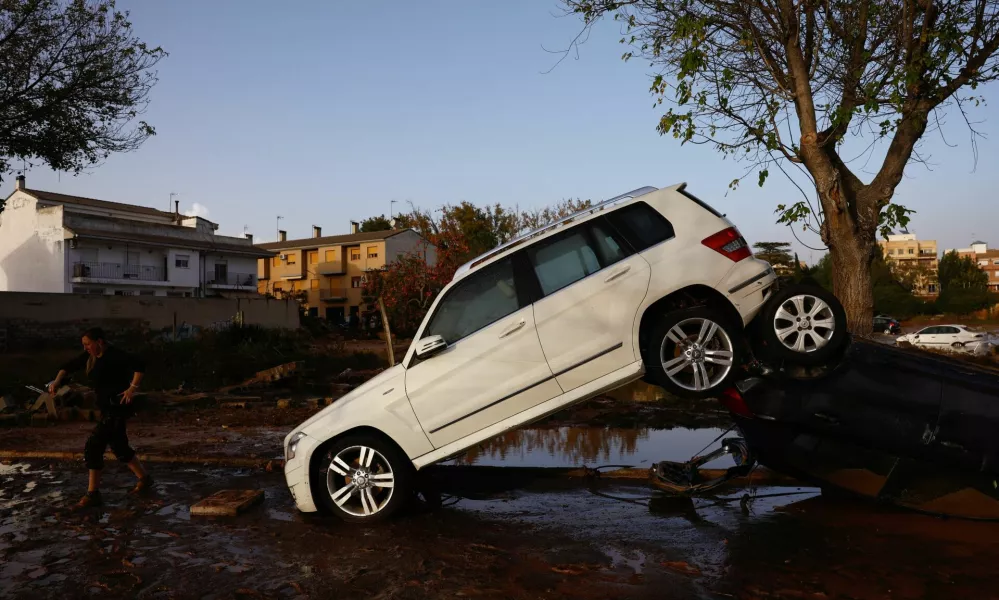 A person walks next to stacked cars after floods in Utiel, Spain, October 30, 2024. REUTERS/Susana Vera