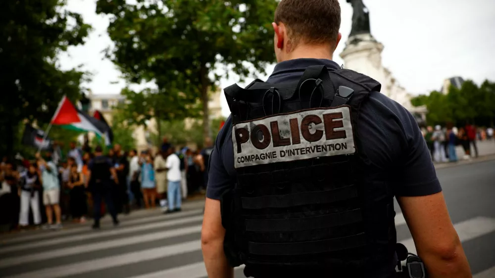 French police stand in position as protesters hold Palestinian flags during a demonstration by social and environmental activists at Place de la Republique, denouncing the Olympics for its environmental record and for driving out homeless people from Paris, on the eve of the opening ceremony of the Paris 2024 Olympic Games, in Paris, France, July 25, 2024. REUTERS/Sarah Meyssonnier