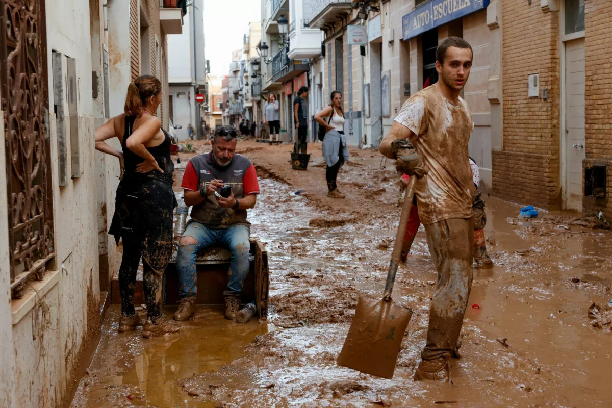 A man with a shovel stands on a mud-covered street in the aftermath of torrential rains that caused flooding, in Paiporta, Spain, October 31, 2024. REUTERS/Eva Manez