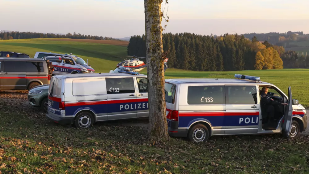 Police vehicles and a police helicopter stand near a field in the village Fraunschalg near Altenfelden, Austria, Monday, Oct. 28, 2024, after people were fatally shot in the area. (AP Photo/laumat/Matthias Lauber)