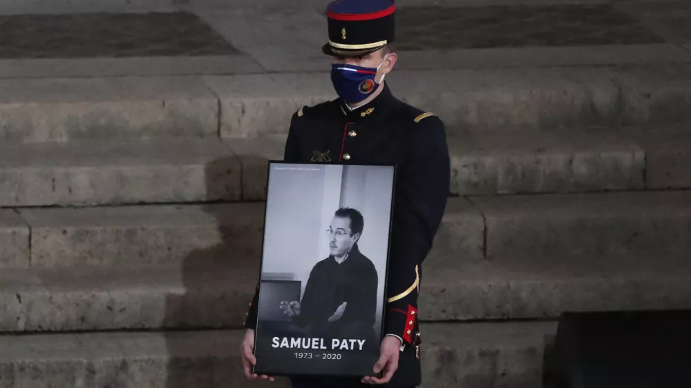 FILE - A Republican Guard holds a portrait of Samuel Paty in the courtyard of the Sorbonne university during a national memorial event, Wednesday, Oct. 21, 2020 in Paris. (AP Photo/Francois Mori, Pool, File)