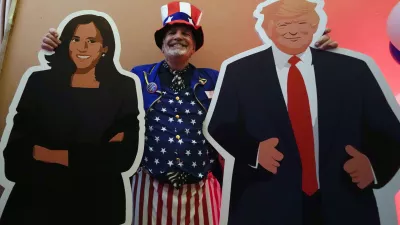 U.S. Consulate General Services Officer Timothy Lockwood poses with cardboards of Kamala Harris and Donald Trump during the Election Night event in Milan, Italy, Tuesday, Nov. 5, 2024. (AP Photo/Luca Bruno)