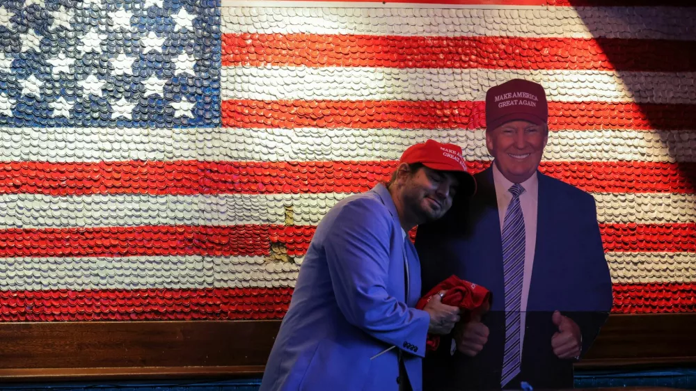 A supporter of Republican presidential nominee former U.S. President Donald Trump embraces a cardboard cut-out of Trump as he reacts to election results while attending the New York Young Republican Club watch party during the 2024 U.S. presidential election, in Manhattan, New York City, U.S., November 6, 2024. REUTERS/Andrew Kelly