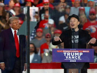 FILE PHOTO: Tesla CEO and X owner Elon Musk speaks as Republican presidential nominee and former U.S. president Donald Trump looks on during a rally at the site of the July assassination attempt against Trump, in Butler, Pennsylvania, U.S., October 5, 2024. REUTERS/Carlos Barria/File Photo