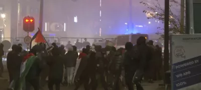 In this image taken from video, a group of pro-Palestinian protesters walk toward police line, with police vans driving in the background, near the soccer stadium in Amsterdam, Netherlands, Thursday, Nov. 7, 2024. (RTL Nieuws via AP)