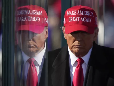 FILE - Republican presidential nominee former President Donald Trump is reflected in the bullet proof glass as he finishes speaking at a campaign rally in Lititz, Pa., Nov. 3, 2024. (AP Photo/Matt Rourke, File)