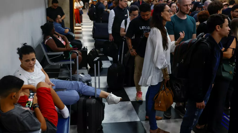 People sit as others queue to rebook a flight at the check in sector after flights were canceled due heavy rains at Congonhas Airport in Sao Paulo, Brazil November 8, 2024. REUTERS/Amanda Perobelli