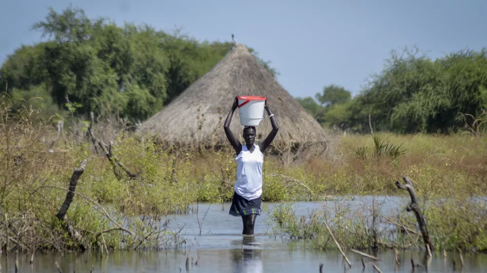 FILE - A woman carries a bucket on her head as she wades through floodwaters in the village of Wang Chot, Old Fangak county, Jonglei state, South Sudan, on Nov. 26, 2020. (AP Photo/Maura Ajak, File)