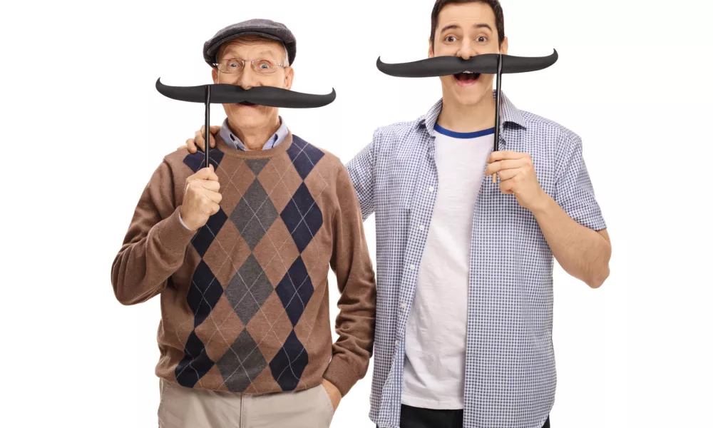 Senior and a young man posing with big fake moustaches isolated on white background / Foto: Ljupco