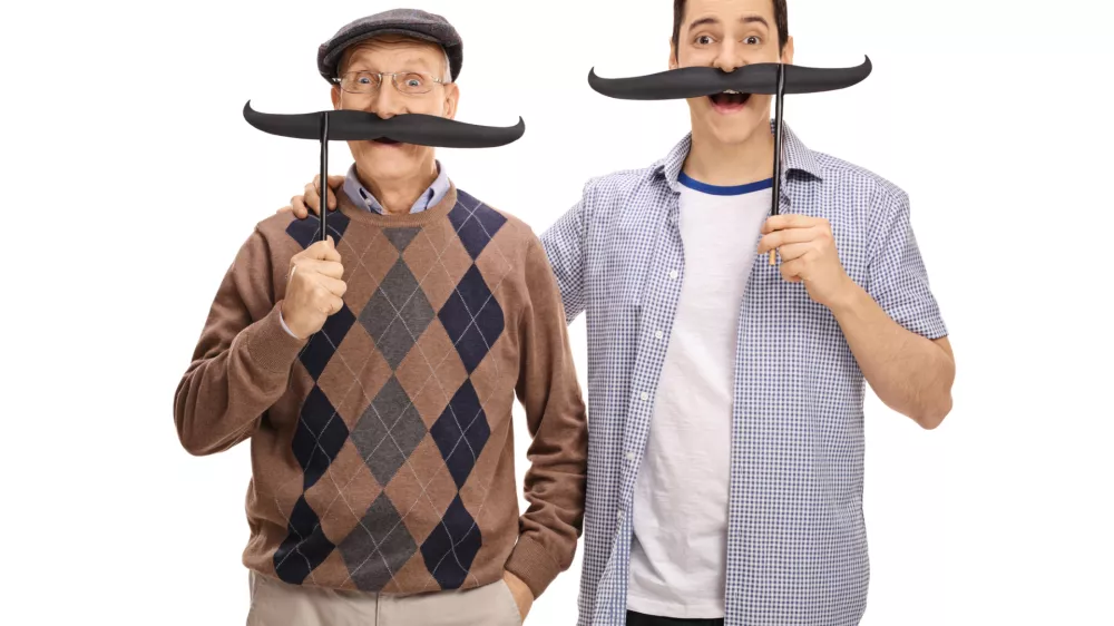 Senior and a young man posing with big fake moustaches isolated on white background / Foto: Ljupco