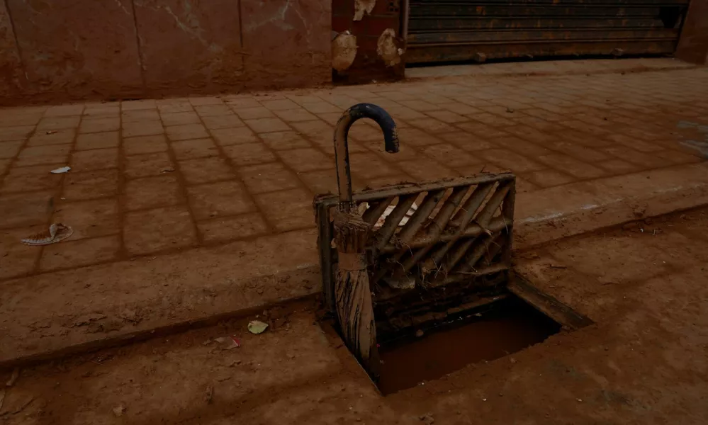 An umbrella is used to keep a storm drain grate blocked by mud open following catastrophic flooding, as Spain braces for torrential rain, in Paiporta, Valencia, November 13, 2024. REUTERS/Vincent West