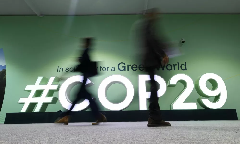 People walk past a COP29 logo during the United Nations Climate Change Conference (COP29), in Baku, Azerbaijan November 14, 2024. REUTERS/Murad Sezer