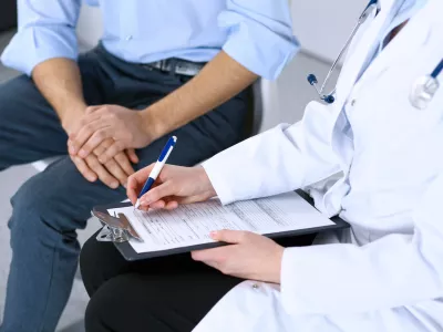 Female doctor holding application form while consulting man patient in hospital. Medicine and healthcare concept. / Foto: Andrei_r