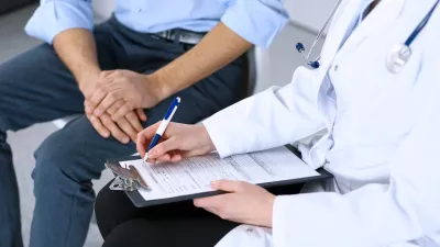 Female doctor holding application form while consulting man patient in hospital. Medicine and healthcare concept. / Foto: Andrei_r