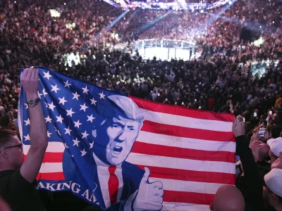 People hold a flag as President-elect Donald Trump arrives at UFC 309 at Madison Square Garden, Saturday, Nov. 16, 2024, in New York. (AP Photo/Evan Vucci)