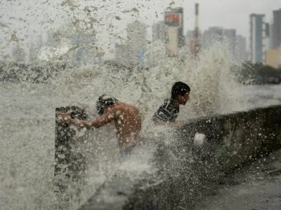 Children play near strong waves from the Pasig River amid Super Typhoon Man-yi, in Manila, Philippines, November 17, 2024. REUTERS/Lisa Marie David