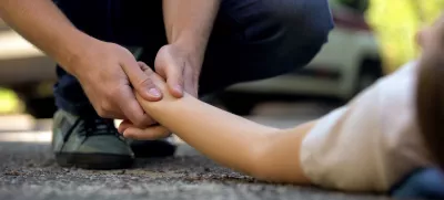 Man holding hand of girl lying on road, unconscious victim of car accident, 911 / Foto: Motortion