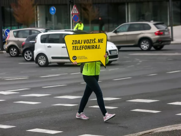 ﻿križišče Šmartinska cesta - Topniška ulica, opozorilna tabla ZDAJ VOZIŠ NE TELEFONIRAJ- 27.03.2019 - Agencija za varnost prometa (AVK) – akcija v okviru katere so promotorji prometne varnosti s sporočilnimi tablami na večjih križiščih opozarjali na nujnost pripenjanja z varnostnim pasom in zmanjšanja uporabe mobilnih telefonov med vožnjo. //FOTO: Luka Cjuha.