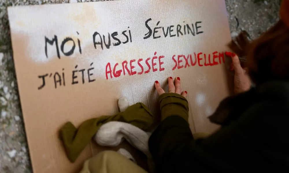 A woman writes on a placard as she attends a demonstration to protest against femicide, sexual violence and all gender-based violence and in support of Gisele Pelicot, the victim of an alleged mass rape orchestrated by her husband Dominique Pelicot at their home, while the trial of Dominique Pelicot and 50 co-accused continues, in front of the courthouse in Avignon, France, November 23, 2024. The placard reads: "Me too Severine, I have been sexually assaulted". REUTERS/Manon Cruz