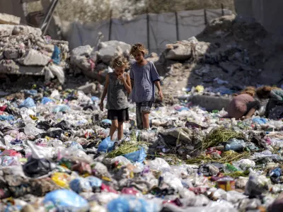 Displaced kids sort through trash at a street in Deir al-Balah, central Gaza Strip, Thursday, Aug. 29, 2024. (AP Photo/Abdel Kareem Hana)